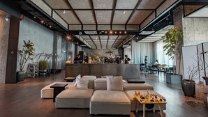 A modern hotel lobby with a reception desk, seating area, and large windows. - Shō Hotel Penang (George Town)