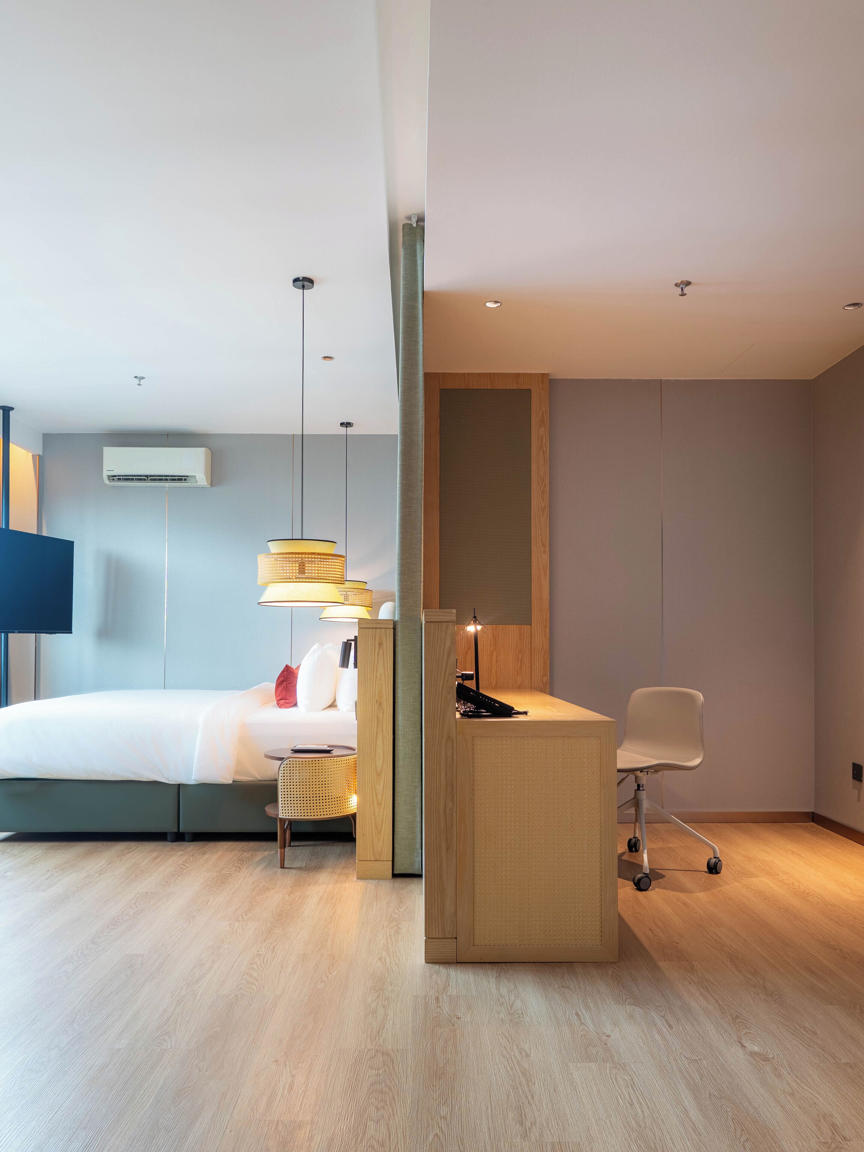 Une chambre d’hôtel moderne équipée d’un lit, d’un bureau, d’une chaise et d’un téléviseur à écran plat.