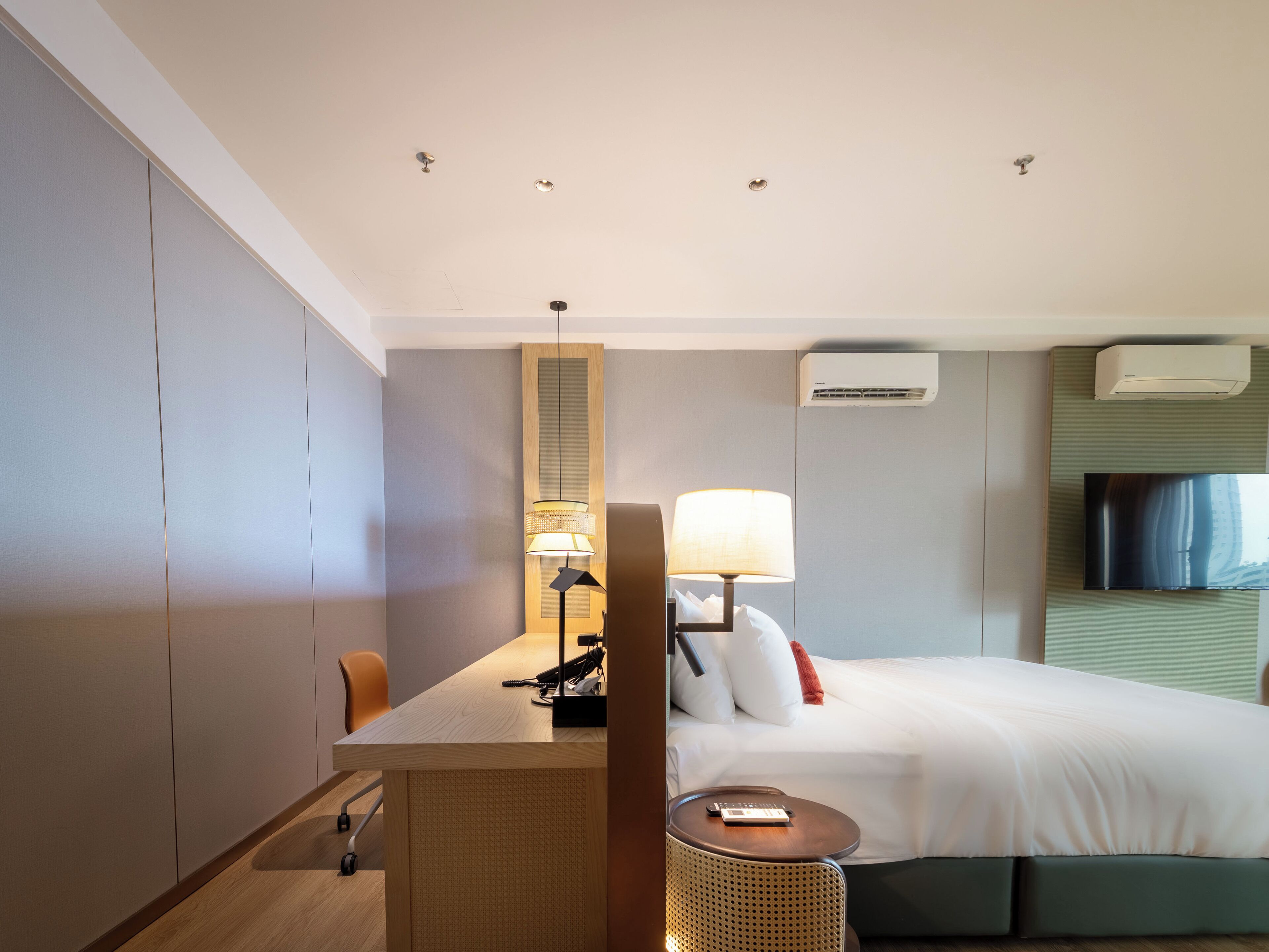 Une chambre d’hôtel équipée d’un lit, d’un bureau, d’une chaise, d’une lampe et d’un appareil de climatisation.