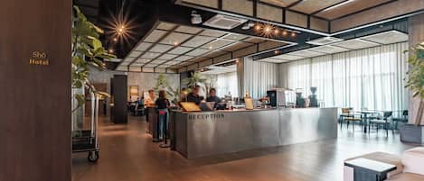 A hotel reception area with a modern design, including a reception desk, seating area, and large windows.