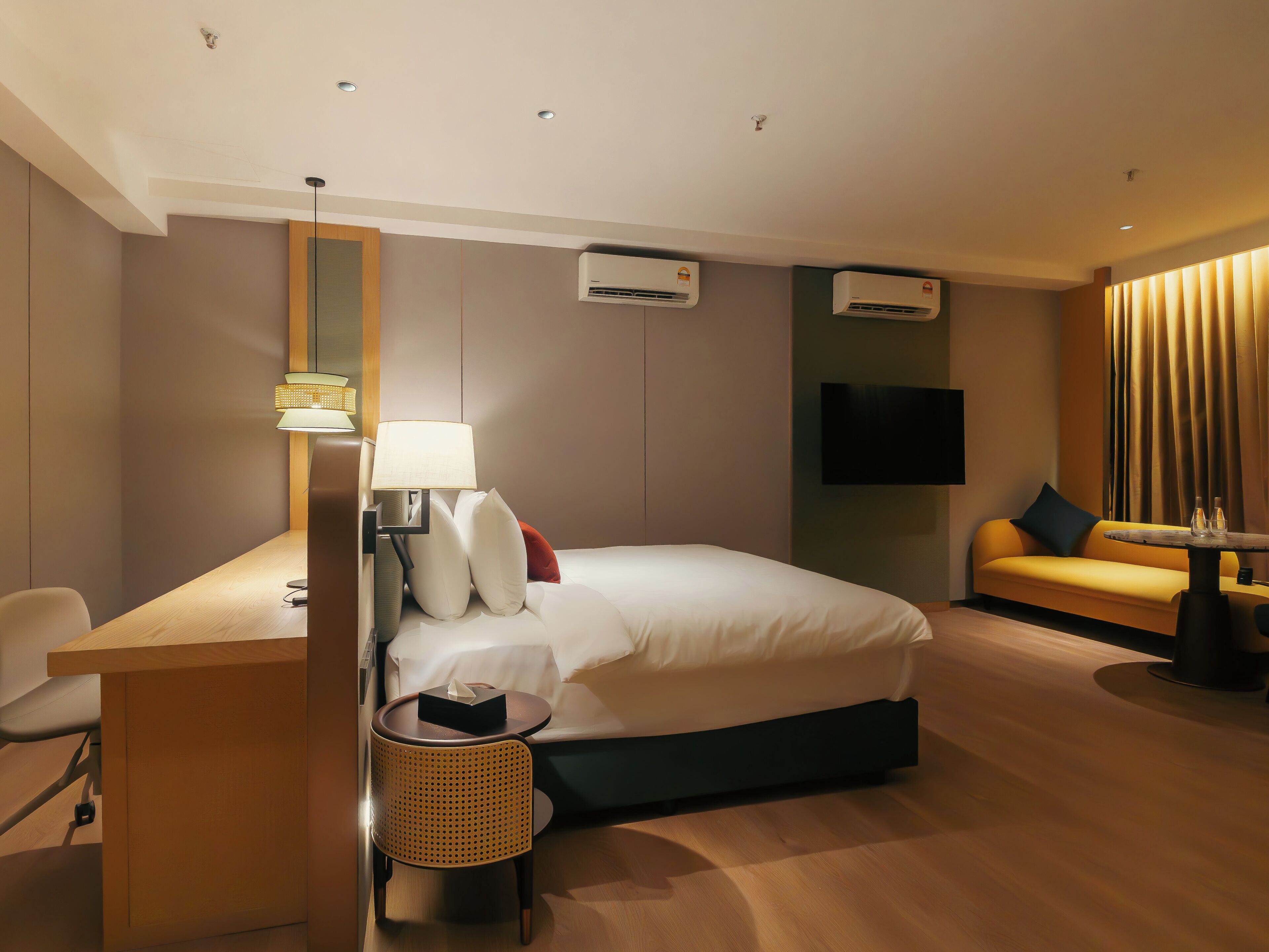 Una habitación de hotel con una cama, un escritorio con lámpara, una silla, un sofá y un televisor.