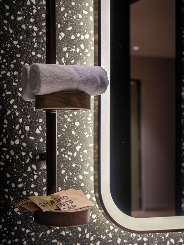 A towel and a brown paper bag hanging on a metal hook, with a window reflecting a room interior.