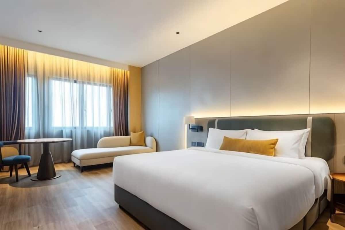 Une chambre d’hôtel avec un grand lit, un bureau, un canapé et une vue sur la ville.