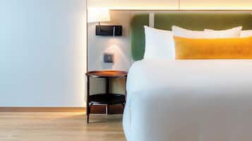 A hotel room with a bed, a nightstand, and a lamp.