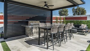 An outdoor patio with a grill, seating area, and a ceiling fan. - Scottsdale 7-BR Oasis: Speakeasy, Pickleball, Golf (Scottsdale)
