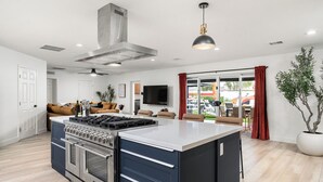 A modern kitchen with a central island, built-in oven, and stainless steel range hood. - Scottsdale 7-BR Oasis: Speakeasy, Pickleball, Golf (Scottsdale)
