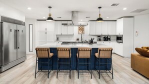 A modern kitchen with a central island, bar stools, stainless steel appliances, and pendant lighting. - Scottsdale 7-BR Oasis: Speakeasy, Pickleball, Golf (Scottsdale)