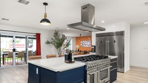A modern kitchen with a central island, stainless steel appliances, and a large window overlooking a patio. - Scottsdale 7-BR Oasis: Speakeasy, Pickleball, Golf (Scottsdale)