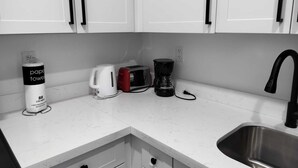 A modern kitchen with white cabinets, a stainless steel sink, a coffee maker, a toaster, and a paper towel dispenser. - Style and comfort in one place 5 (Miami)
