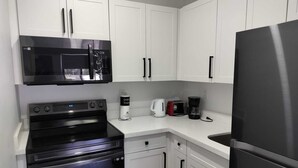 A modern kitchen with white cabinets, a black refrigerator, a microwave, a stove, and a coffee maker. - Style and comfort in one place 5 (Miami)