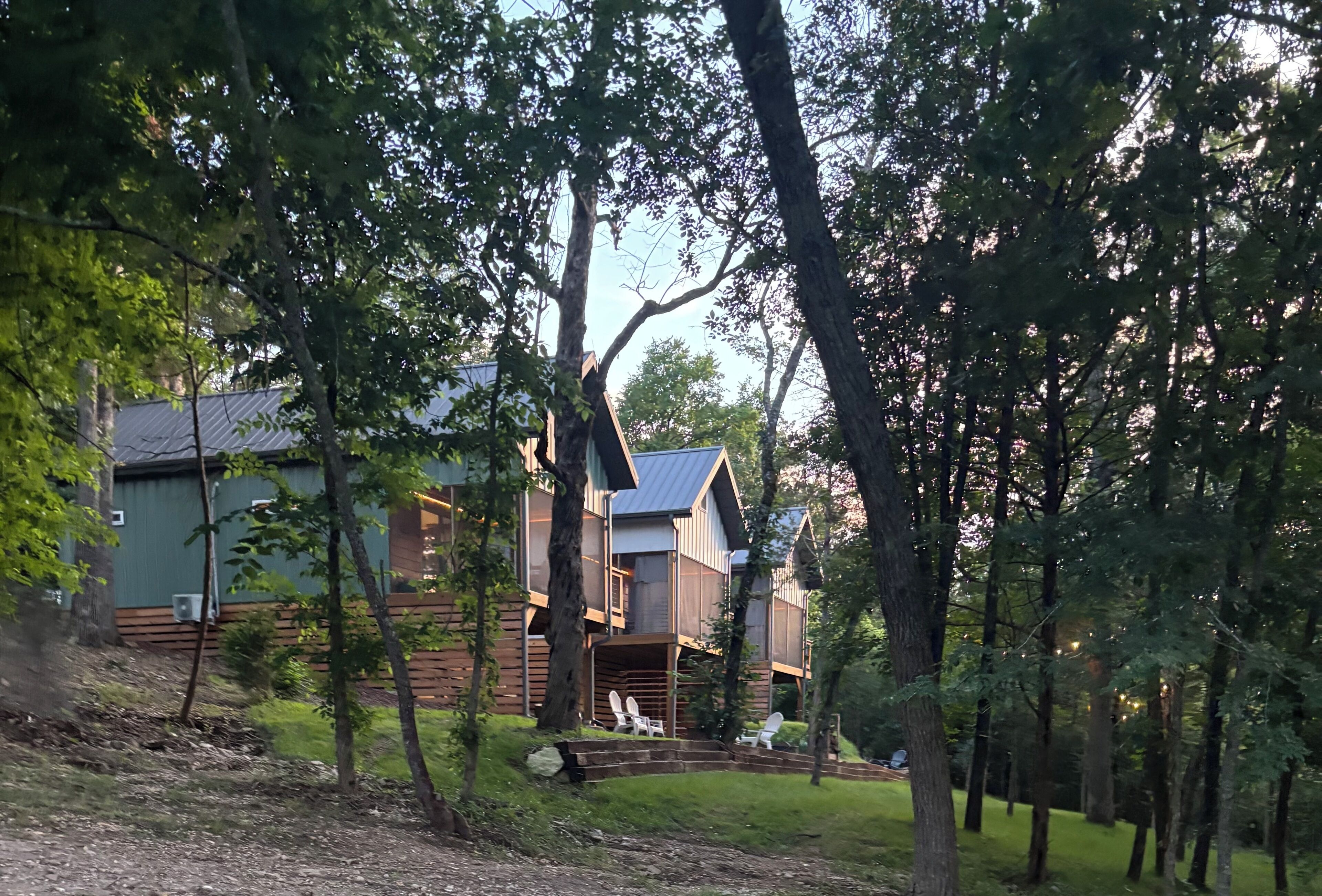 Een houten chalet, omringd door bomen en een gazon.