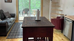 Un vaste espace de vie doté d’un plafond en bois, d’un escalier menant à un niveau supérieur, d’une table à manger et d’un coin cuisine.
