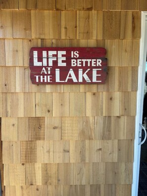 A wooden wall with a sign that reads "Life is better at the lake."