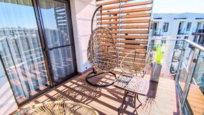 A balcony with a wicker chair, a woven chair, and a woven floor chair. - Apartment B 406 by Interhome (Kolobrzeg)