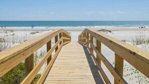 A wooden boardwalk leading to a beach with clear skies.