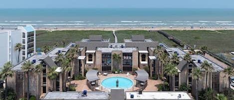 Un complexe hôtelier doté d’une piscine centrale, de nombreuses chambres et offrant une vue sur la plage.