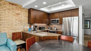 A modern kitchen with dark wooden cabinets, stainless steel appliances, and a central island with seating.