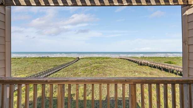 A wooden deck with a view of a beach and ocean. - Charming 2-Bedroom Condo. Unbeatable Beach Access! (South Padre Island)
