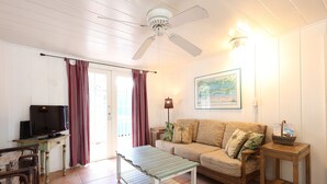 Un salon équipé d’un téléviseur, d’un canapé, d’une table basse et d’un ventilateur de plafond.