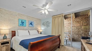 Een slaapkamer met een houten bed, een plafondventilator en een bakstenen muur.