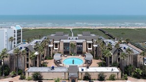 Een resort met een centraal gelegen zwembad, diverse gastenkamers en uitzicht op het strand.