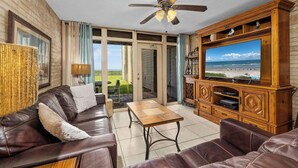 A living room with a leather sofa, a wooden entertainment center, and a television displaying a beach scene.