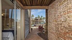 A narrow outdoor corridor with a brick wall on one side and a sliding glass door on the other.