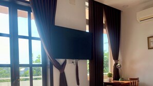 Ein Hotelzimmer mit einem Bett, einem Schreibtisch, einem Sessel, einem Fernseher und einem Fenster mit Vorhängen.