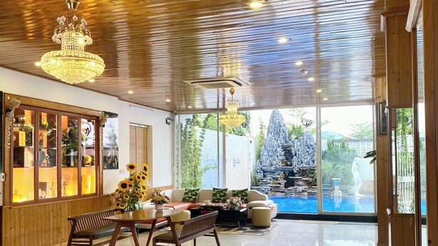 Eine geräumige Lobby mit Holzboden, einem Chandelier, einer Sitzecke mit Tisch und Stühlen sowie Blick auf eine Gartendusche.