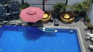 Ein Pool auf dem Dach mit Sprungbrett, Liegestühlen und Sonnenschirmen.