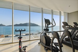 Una palestra con attrezzi e una grande vetrata vista mare.