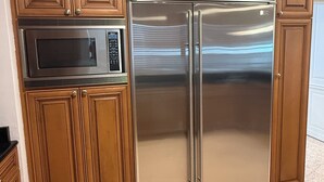 A kitchen with wooden cabinets, a stainless steel refrigerator, and a microwave.