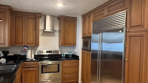 A kitchen with wooden cabinets, stainless steel appliances, and a black countertop.