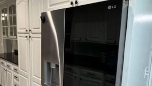 Una cocina moderna con armarios blancos, un refrigerador de acero inoxidable y piso de baldosas.
