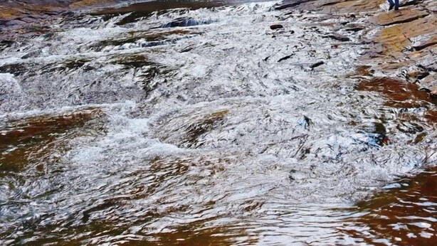 A waterfall in a forested area with a person walking towards it. - Makeliya Jungle & Waterfall Tour (Kelinkanda)