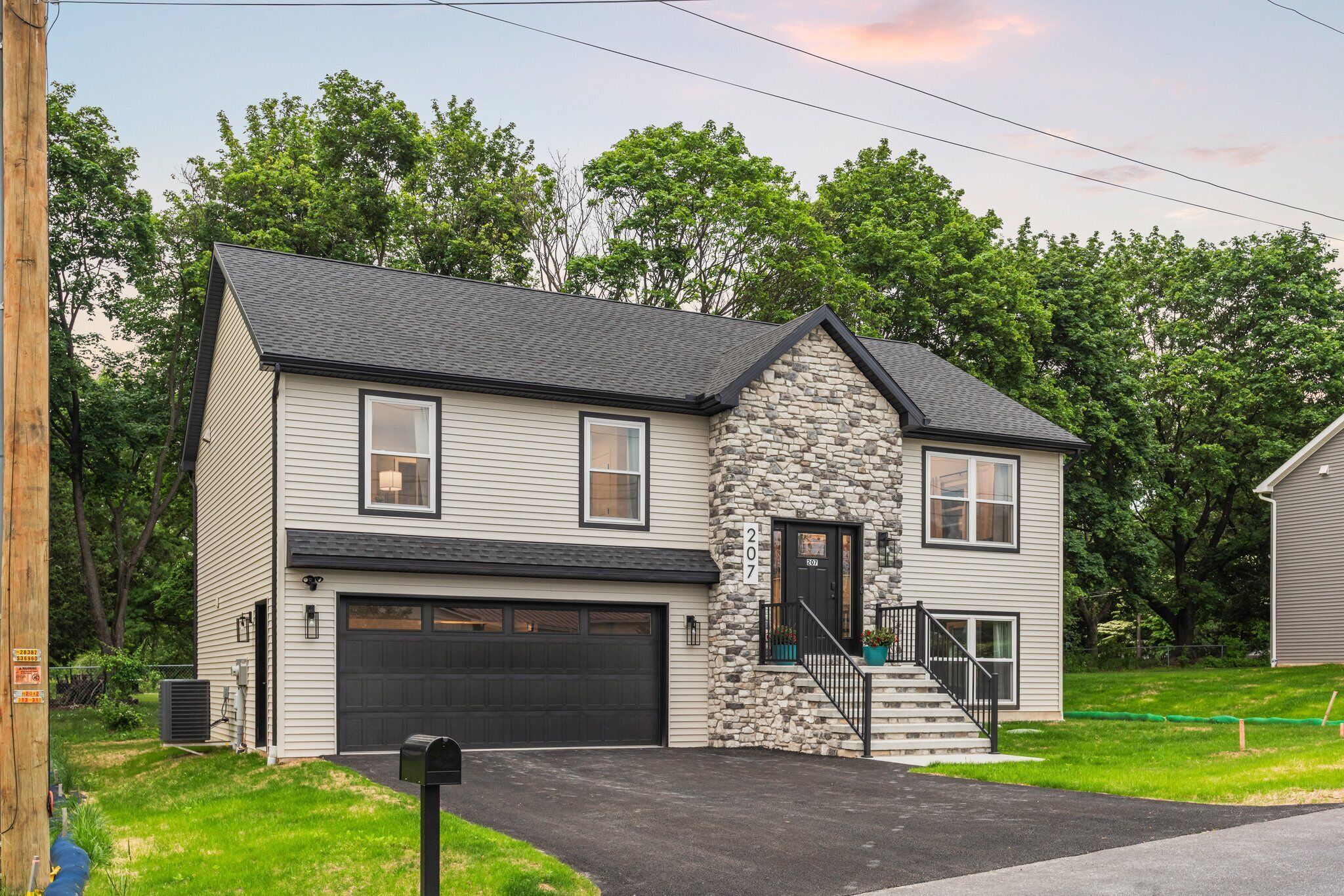 A two-story house with a stone facade, a garage, and a front porch with a staircase.