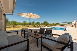 An outdoor seating area with a pool, lounge chairs, and umbrellas.