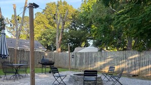 A backyard patio with a fire pit, outdoor furniture, and a wooden pergola.