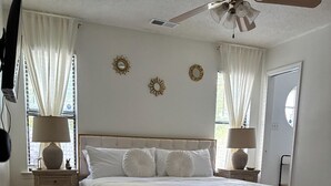 A bedroom with a bed, bedside tables, a bench, and a ceiling fan.
