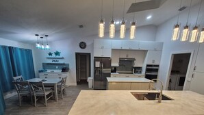A modern kitchen with a central island, stainless steel appliances, and pendant lighting.