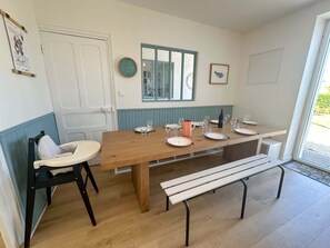 Ein Essbereich mit einem Holztisch, gedeckt für vier Personen, einer Bank und einem Hochstuhl.