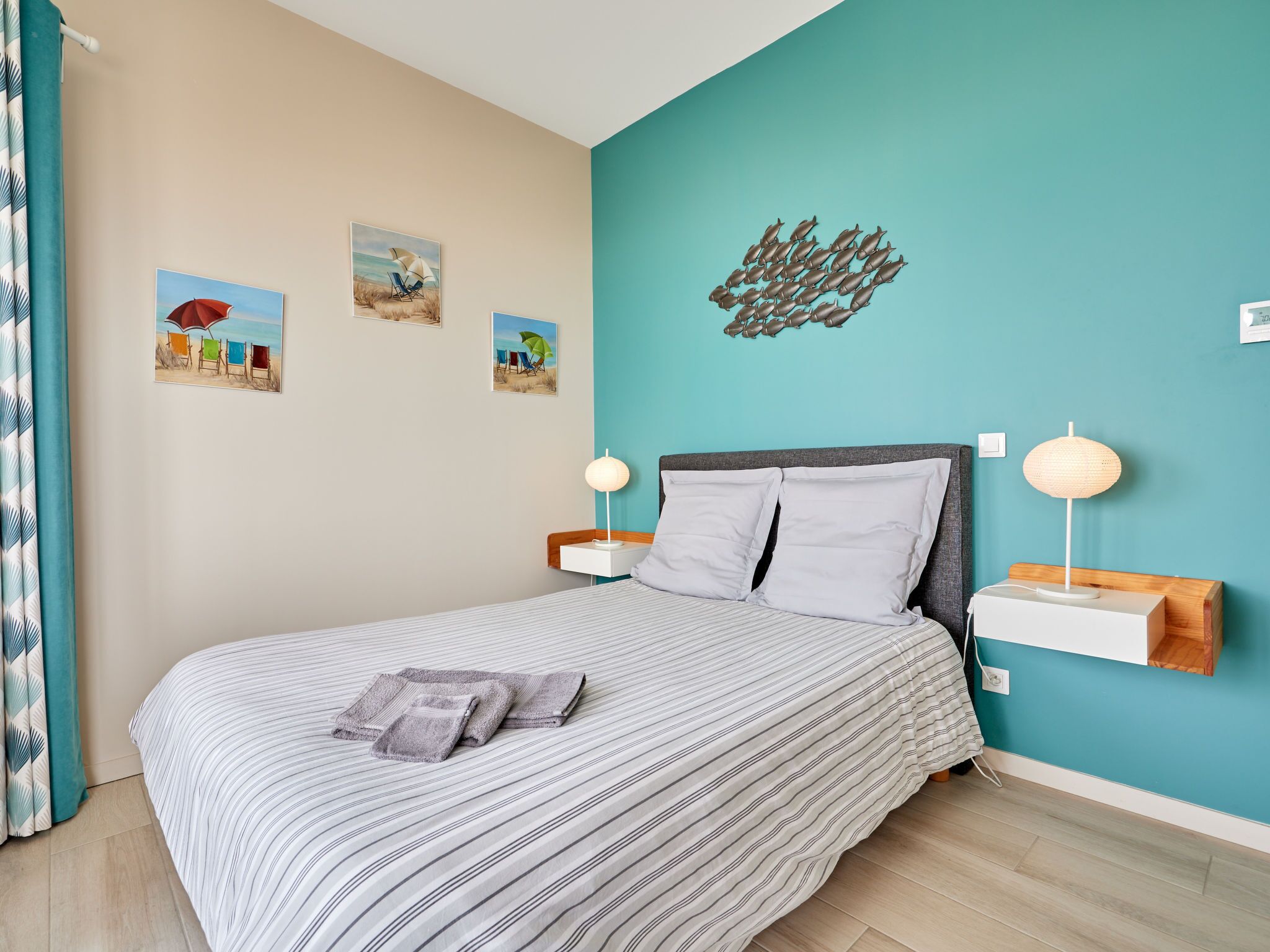 Un dormitorio con una cama, dos mesitas de noche y tres cuadros colgados en la pared.