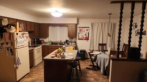 A compact kitchen with wooden cabinets, a central island, and a dining area with a table and chairs.