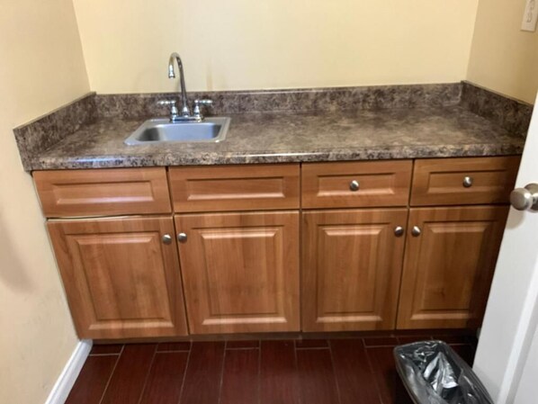 A small kitchen with a granite countertop, wooden cabinets, and a stainless steel sink.