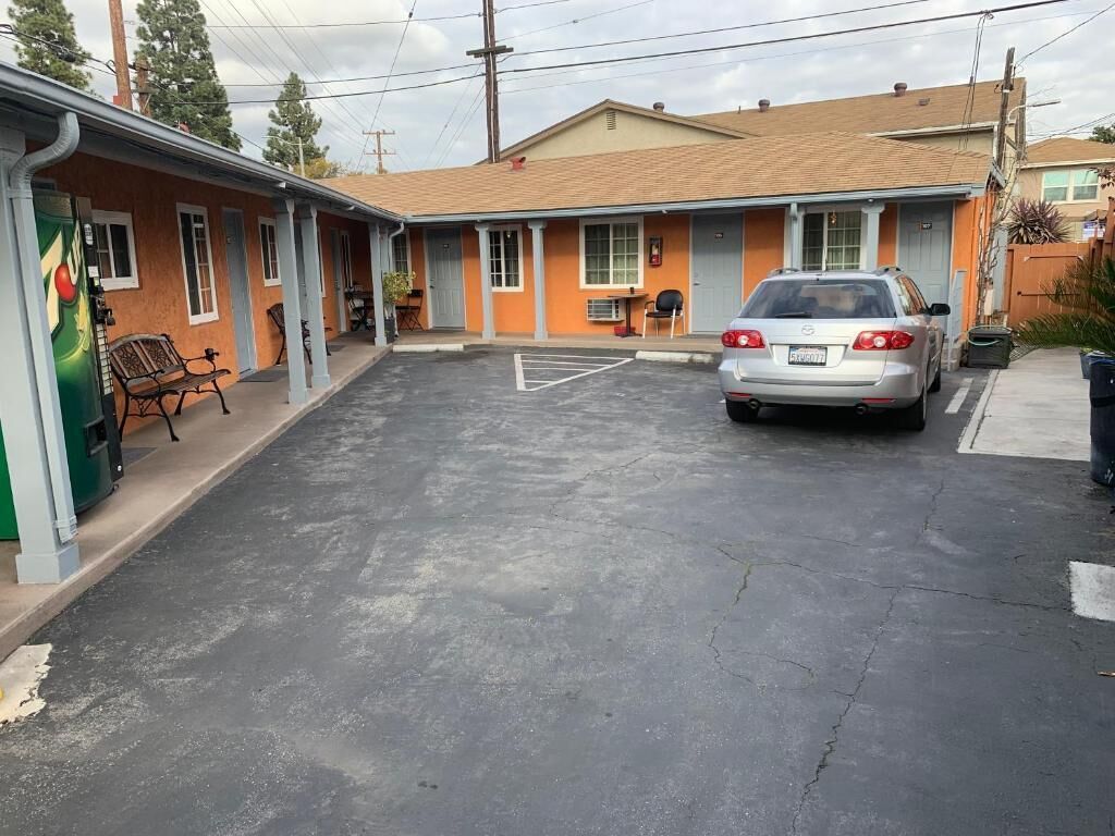 A motel with a parking lot, a car parked in the lot, and a building with a flat roof.