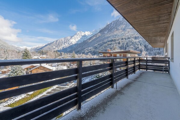 A balcony with a view of snow-covered mountains and a clear sky.