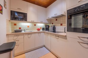 A modern kitchen with white cabinets, a built-in microwave, a coffee machine, and a Siemens oven.