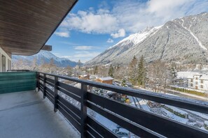 Un balcón con vistas a una montaña nevada y un pueblo.