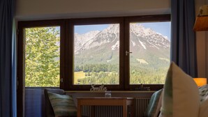A hotel room with a bed, a table, and a view of mountains.