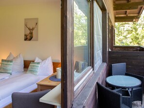 A room with a bed, a small table, and a window overlooking greenery. - Studio Esche 2 by Interhome (Ellmau)